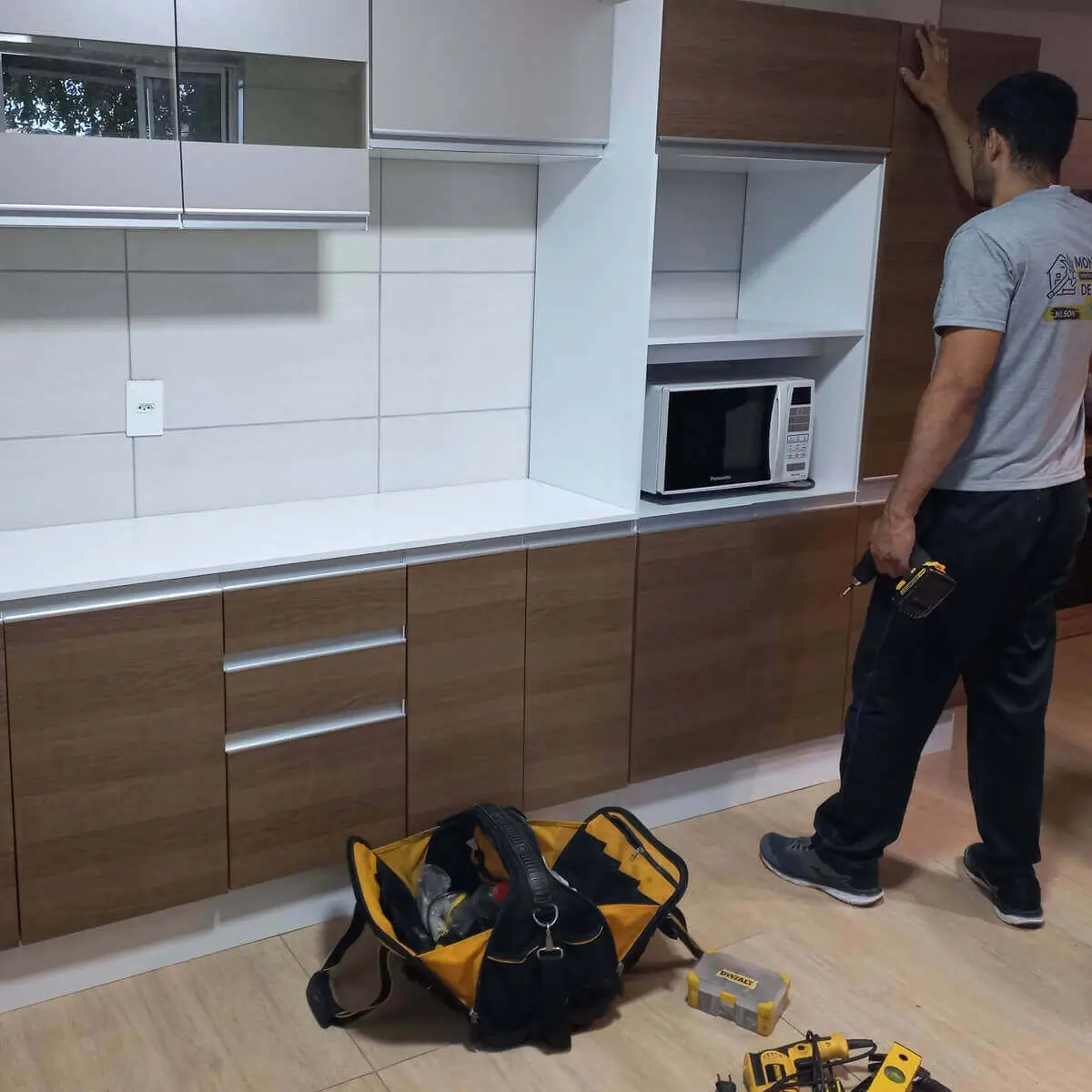 Montador de móveis realizando montagem de armário de cozinha planejada no bairro do Leme, RJ